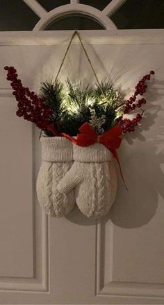 a christmas stocking hanging on a door with red berries and greenery in it