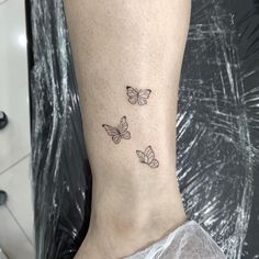 three small butterflies on the ankle tattoo design for womens feet and ankles, all in black ink