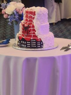 This is a 3 tier wedding cake on a table. One side of it is white with rosettes on the top and bottom tier and just a dot pattern on the middle tier.  The other side of the cake has a red background with white webbing. There is a Spiderman emblem on middle tier and the outline of a city on the bottom tier. Spiderman Wedding Cake, Spiderman Birthday Cake Ideas, Hello Kitty And Spiderman, Spiderman Birthday Cake, Spiderman Gifts, Spiderman Theme, Spiderman Cake, Birthday Cake Ideas