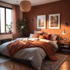 a bedroom with an orange wall and bed in the corner, two pictures on the wall