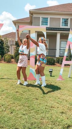 two girls are standing in front of the letters