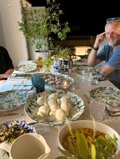 two men sitting at a table with plates and bowls of food in front of them