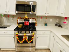 a kitchen with white cabinets and stainless steel stove top oven, decorated with fruit garlands