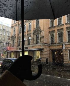 a person holding an umbrella on a city street in the rain while it's raining