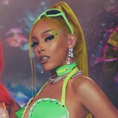 a woman with bright yellow hair and green eyeshades is wearing neon clothing while standing in front of a colorful background