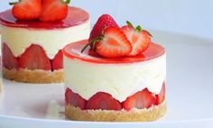 two desserts with strawberries on top are sitting on a white plate, ready to be eaten