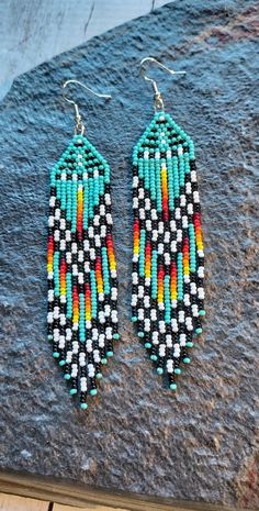 a pair of colorful beaded earrings sitting on top of a rock