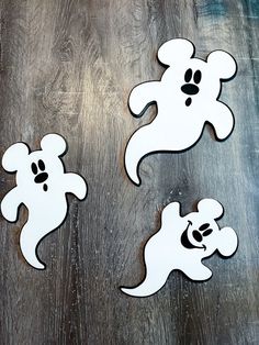 three wooden cut outs depicting mickey mouses and a panda bear on a wood table