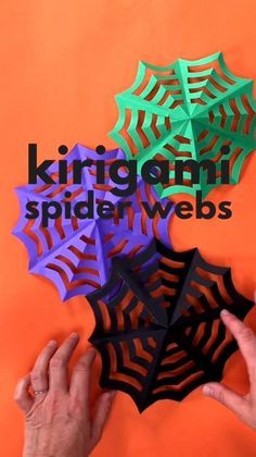 two hands are holding paper spider webs on an orange background with the words king george's spider webs