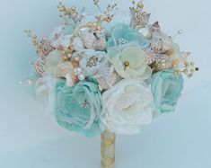 a bridal bouquet with seashells, pearls and flowers on the stems is shown