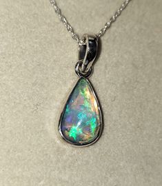 Introducing a breathtaking pear-shaped opal pendant, elegantly bezel set in sterling silver. This enchanting piece of jewelry is a true testament to the ethereal beauty of opals. The pear-shaped opal, with its mesmerizing play of colors, evokes a sense of magic and wonder. Its iridescent hues dance within the gemstone, exhibiting flashes of fiery reds, vibrant greens, and shimmering blues. As light interacts with the opal, it reveals a captivating display of ever-changing colors. Nestled securely within a sleek silver bezel, the opal takes center stage, commanding attention with its captivating presence. The bezel setting not only protects the gemstone but also enhances its natural beauty, allowing the opal to be the star of the show. The sterling silver setting complements the opal perfec Iridescent Teardrop Jewelry For Formal Occasions, Silver Opal Drop Jewelry, Formal Pear-shaped Opal Jewelry, Pear-shaped Opal Jewelry For Formal Occasions, Formal Opal Pear-shaped Jewelry, Formal Teardrop Opal Pendant Jewelry, Formal Opal Teardrop Pendant Jewelry, Iridescent Teardrop Gemstone Jewelry, Silver Pear-shaped Cabochon Jewelry