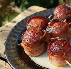 bacon wrapped meats on skewers are sitting on a plate with toothpicks