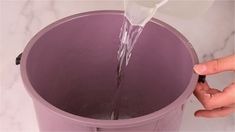 someone pouring water into a purple trash can