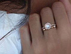 a woman's hand with a ring on it and a white shirt behind her