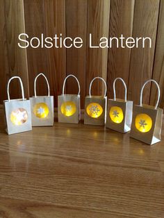 small bags with lights in them sitting on a wooden table next to the words solstic lanternen