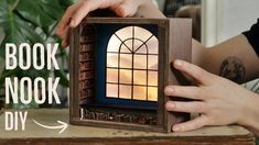 a person holding up a book shaped like a window