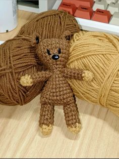 a brown teddy bear sitting next to a ball of yarn on top of a table