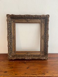 an old gold frame sitting on top of a wooden table