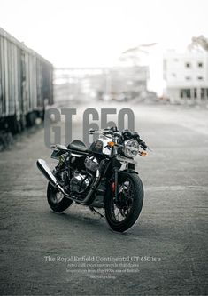 a black motorcycle parked on the side of a road next to a train track and buildings