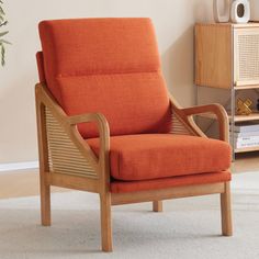 an orange chair sitting on top of a carpeted floor next to a book shelf