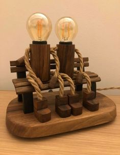 two light bulbs sitting on top of a wooden bench with rope wrapped around the ends