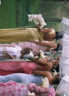 several women are laying on the ground with umbrellas over their heads and flowers in their hair