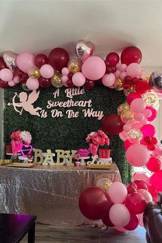 a table topped with balloons and cake next to a sign that says it's a little sweetheart to on the way