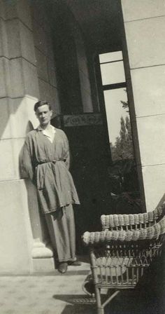 an old black and white photo of a woman standing in front of a door