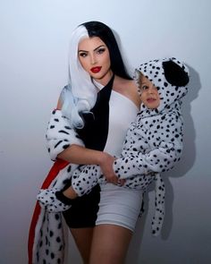 a woman holding a child dressed in dalmatian costumes and posing for the camera