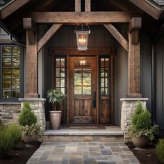 a wooden door with two planters on each side and a light hanging above it