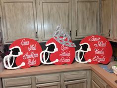 three red football helmets with silver crowns on them sitting on top of a kitchen counter