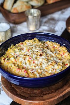 a blue bowl filled with food sitting on top of a wooden table next to bread