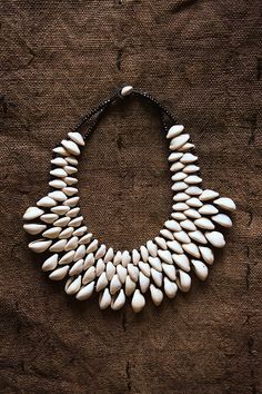 Expertly handcrafted, this African Cowrie Shell Necklace is a statement piece that adds unique and exotic flair to any outfit. Made from genuine cowrie shells, each necklace is one-of-a-kind and showcases the beauty of African craftsmanship. Elevate your style with this stunning, handmade jewelry. Length: 9" White Handmade Artisan Shell Necklace, Unique Handmade White Shell Necklace, Unique Handmade Cowrie Shell Necklace, Traditional Cowrie Shell Jewelry, Traditional White Cowrie Shell Jewelry, White Artisan Shell Jewelry, Artisan White Shell Jewelry, Handmade White Cowrie Shell Necklaces, Unique Handmade Cowrie Shell Jewelry