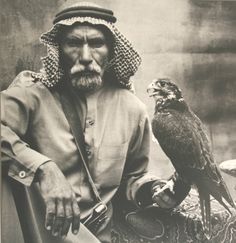 an old photo of a man with a falcon on his arm and another bird sitting next to him