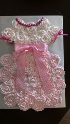 a white card with pink ribbon and roses on the front, sitting on top of a table