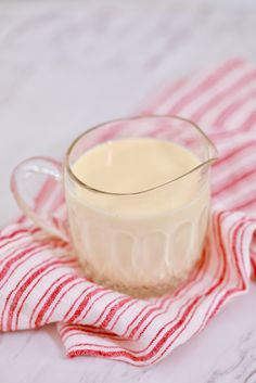 a glass mug filled with liquid sitting on top of a red and white striped towel