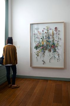 a woman standing in front of a painting on the wall next to a wooden floor