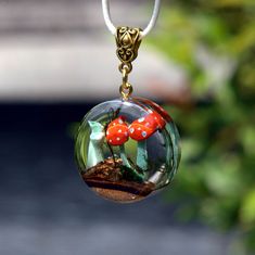 a close up of a glass ball with two mushrooms in it hanging from a chain