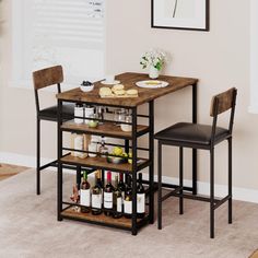 two chairs and a table with wine bottles on it in front of a white wall