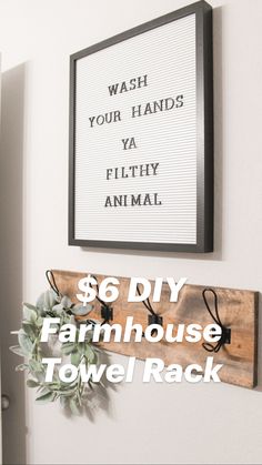 a wooden sign hanging on the wall above a coat rack with hooks and a plant