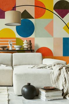 a living room with a couch, table and lamp in front of a colorful wall