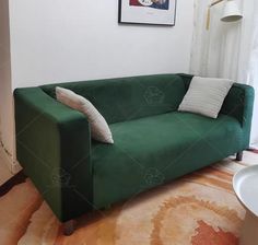 a green couch sitting on top of a wooden floor