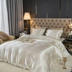 a white bed sitting in a bedroom next to a chair and lamp on a table