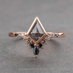 a diamond ring with black and white diamonds on it's sidestone, sitting on a gray surface