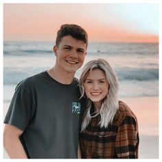 a man and woman standing next to each other on top of a beach near the ocean