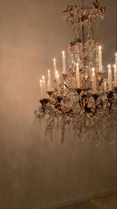 a chandelier with many lit candles hanging from it's sides in a room