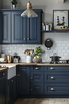 a kitchen with blue cabinets and white tile backsplashes, wood flooring