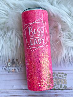 a pink and gold glitter tumbler with the words boss lady on it sitting next to white fur