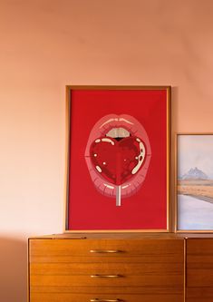 an art piece is on top of a dresser in front of a red poster with a heart