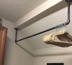 a wooden hanger with clothes hanging from it's hooks in a room that has white walls and wood cabinets